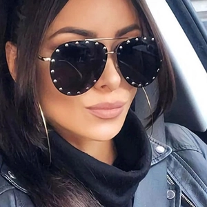 Close-up of pilot style sunglasses with silver rivets and black lenses worn in a car