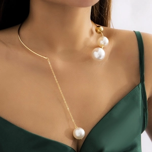 Detail of gold choker necklace featuring asymmetric tassels and large white pearls
