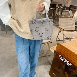 Detail of grey corduroy tote bag featuring black smiley patterns and wide handles