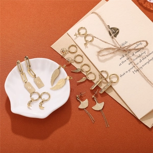 18K gold plated stainless steel earring set with moon and wing charms on orange fabric