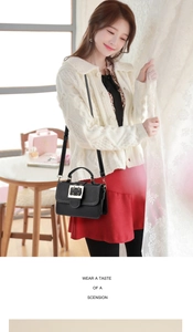 Close-up of black retro square buckle crossbody bag on model in knit cardigan