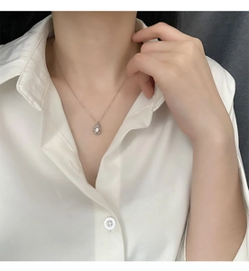 Detail of French vintage necklace with freshwater pearl pendant on white shirt