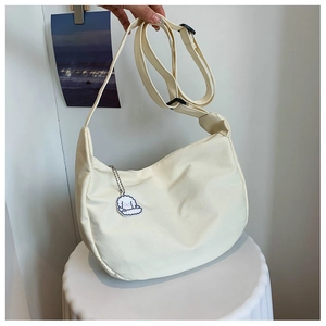 Detail of beige canvas hobo bag with adjustable strap and cute sheep pendant charm