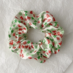 Detailed close-up of cream satin scrunchie with festive Christmas tree and hat patterns