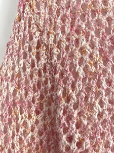 Macro shot of pink and white crochet knit fabric with subtle sequin details and texture