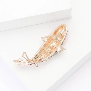 Detailed back view of a gold fish brooch showing the pin clasp and red rhinestone accents