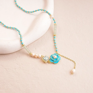 Close-up of elegant flower necklace with blue beads and pearl charms on white tray