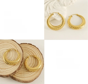 Dettaglio macro di orecchini a cerchio dorati con texture a spirale su legno e gesso