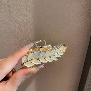 Detailed view of golden leaf hair claw clip with opal stones and rhinestone accents