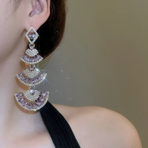 Detail of elegant gold layered fringe earrings with purple stones on a model