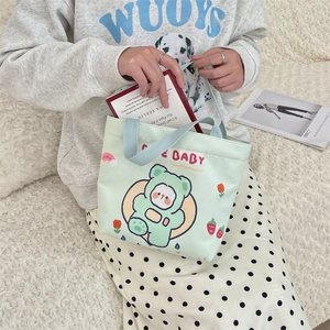 Detail of light green canvas tote bag featuring a cute cartoon bear print and handle