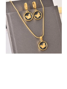 Detail of gold butterfly necklace and earring set displayed on a dark jewelry stand