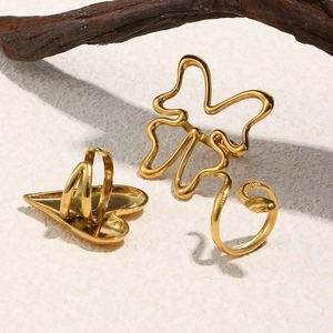 Detail shot of 18K gold plated heart, butterfly, and snake ring set on textured background
