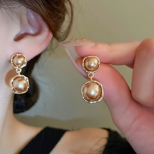 Gros plan de boucles d'oreilles dorées vintage avec perles et monture texturée