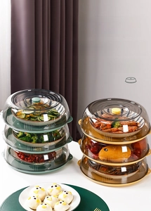 Detail view of multi-layer stackable food covers in green and gold with transparent lids