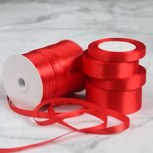 Detail of assorted red satin ribbons in various widths on grey marble background