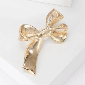 Elegant gold bow brooch featuring a textured alloy finish and a secure back pin closure