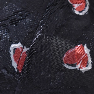Detailed macro view of black jacquard fabric with red heart pattern on baseball cap