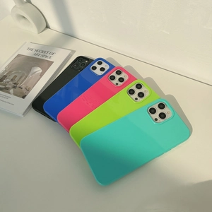 Five vibrant colors of silicone iPhone cases stacked on a minimalist white aesthetic table