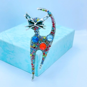 Vintage silver cat brooch with colorful rhinestones on a blue jewelry gift box
