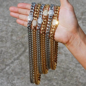 Hand holding gold and silver Cuban link necklaces with iced out rhinestone buckles