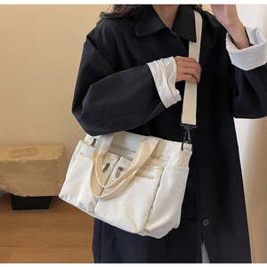 Detail of off-white corduroy tote bag showing multiple pockets and adjustable strap