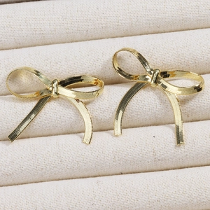 Macro shot of elegant golden bow earrings with intricate textured metallic finish