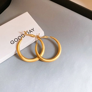 Detailed close-up of matte gold plated hoop earrings on a minimalist background