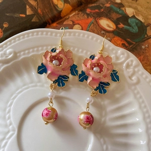 Detail von Vintage-Blumenohrringen mit Kunstperlen und Goldperlen auf einer Keramikschale