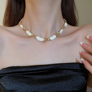 Détail du collier à nœuds croisés en émail blanc sur la clavicule du mannequin