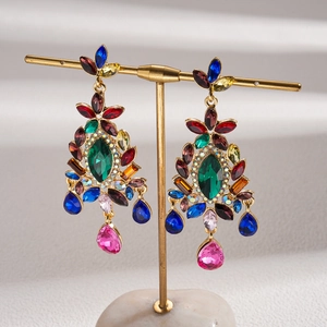 Detailed shot of bohemian floral drop earrings with colorful crystals on a gold stand