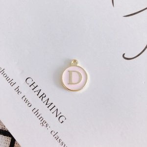Detailed view of a round pink enamel 'D' letter pendant with gold alloy plating for DIY jewelry