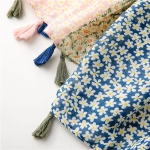 Close-up of floral print scarf with tassels in pink and green on a white background