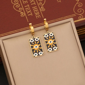 Detailed macro of gold celestial earrings with black enamel evil eye and sun motifs