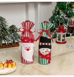 Close-up of knitted Santa and Snowman wine bottle covers on a festive Christmas dining table