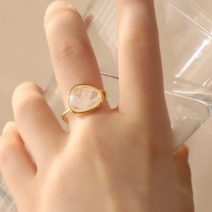 Minimalist 925 sterling silver gold ring with white crystal worn on hand with a glass