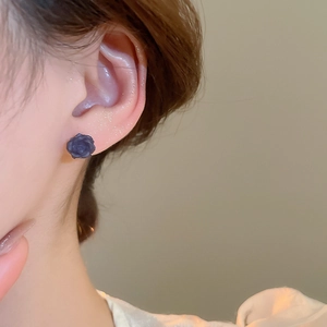 Gros plan détaillé de boucles d'oreilles roses en résine mate violet foncé sur l'oreille