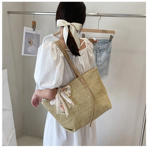 Detail of straw tote bag with delicate lace floral accent and slim brown shoulder strap