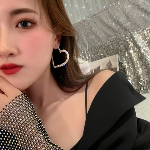 Luxe oversized heart-shaped rhinestone hoop earrings worn by a model in silver finish