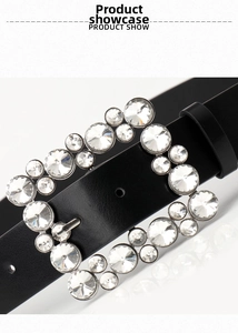 Detail of black belt showing square buckle encrusted with clear crystals on a white surface