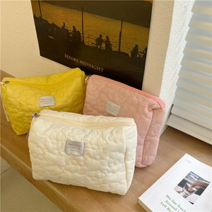 Close-up of quilted floral cosmetic bags in macaron colors with soft fabric texture