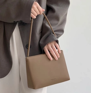 Close-up of minimalist taupe leather crossbody bag with slim shoulder strap for women