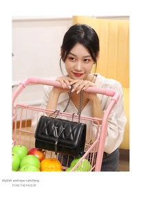 Chic black quilted shoulder bag with metal V logo and stylish tassel on a pink background