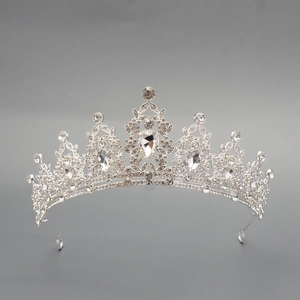 Detailed view of silver luxury crown featuring intricate scrollwork and pear-shaped crystal