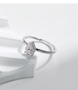 Macro shot of 925 silver ring featuring a pear-cut moissanite stone on a white prop