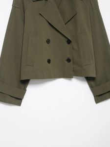 Detailed macro view of army green double-breasted jacket showing fine twill fabric texture