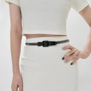 Detail of thin dark grey metallic waist belt with square buckle on a white dress