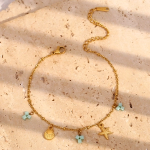 Détail de breloques étoile et coquillage en or 18K avec perles menthe sur chaîne acier