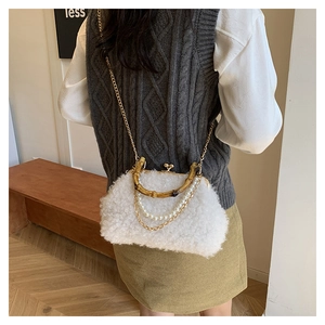 Detail of white faux fur shell bag with bamboo handle and pearl chain on a model
