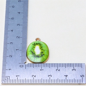 Macro shot of a 22mm kiwi fruit alloy pendant measured with a steel ruler for size